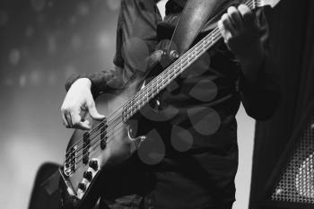 Rock and roll music, bass guitar player on a stage near speakers, selective focus