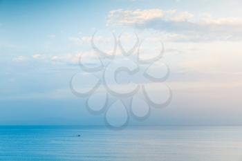 Seascape under cloudy blue sky, small boat goes on sea water, negative space composition