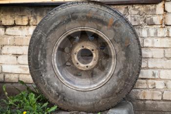 Old used car wheel stands near grungy brick wall