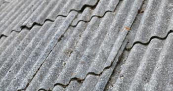 Old gray corrugated fibre cement roofing, background photo with selective focus
