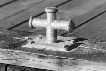 Black and white square photo with mooring bollard mounted on wooden pier, port equipment