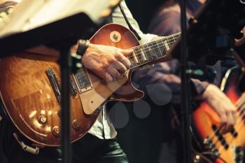 Rock and roll music background, guitar players on a stage, selective focus and  retro tonal correction filter, old instagram style