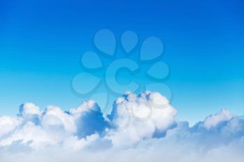 Cloudscape with white cumulus clouds in bright blue sky, natural photo background