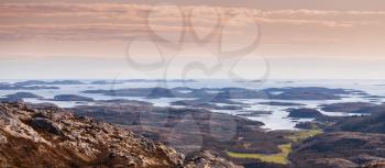 Panoramic Norwegian coastal landscape with sea, sky and rocky hills in springtime