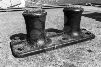 Big mooring bollard mounted on concrete pier in port, black and white retro style photo