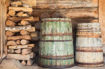 Old wooden barrels and stack of firewood, vintage Russian rural objects