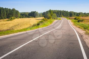 Empty turning rural highway under blue sky in summer day, European road landscape