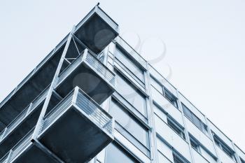 Abstract contemporary architecture fragment, walls and balconies made of glass and concrete. Blue tonal correction filter photo effect