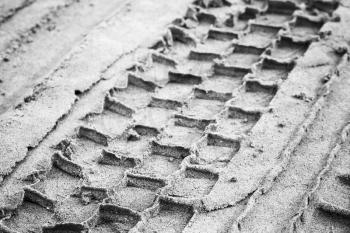 Tire track on gray sandy ground, abstract monochrome transportation background photo with selective focus