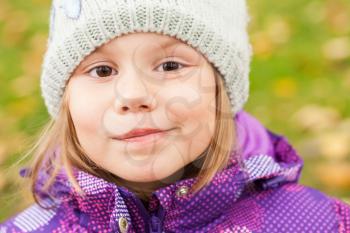 Funny smiling Caucasian little girl, closeup outdoor portrait, walking in autumnal park