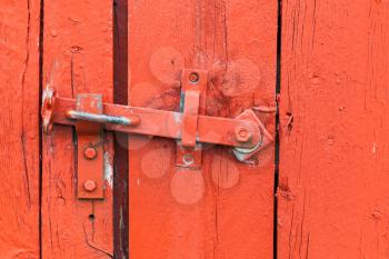 Old metal latch on red wooden door, close-up photo