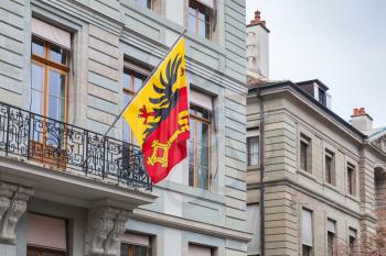 Geneva city, Switzerland.  Flag with coat of arms mounted on old house wall showing the Imperial Eagle and a Key of St. Peter