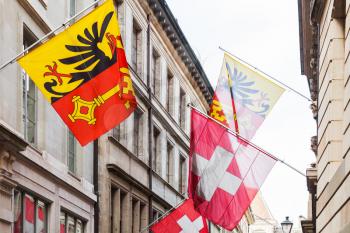 Geneva city, Switzerland. Swiss National and City flags mounted on old house wall