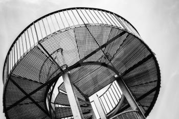 Round metal tower with internal spiral stairway, abstract industrial architecture fragment