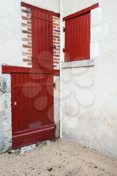Corner of an old European house with red wooden doors and windows, vertical photo