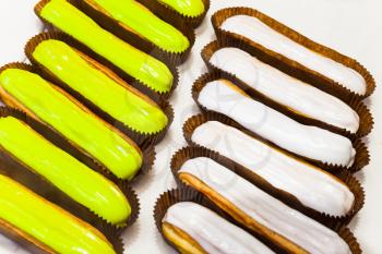 Rows of colorful eclairs, small, soft, log-shaped pastry filled with cream