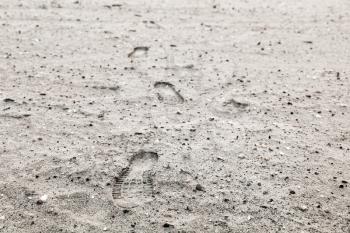 Human footprints in gray sandy ground, background photo with selective focus