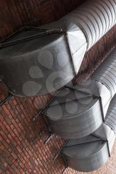 Outdoor ventilation tubes mounted on red brick wall
