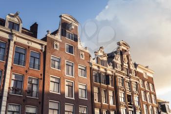 Traditional living houses of old Amsterdam, Netherlands. Facades over cloudy sky