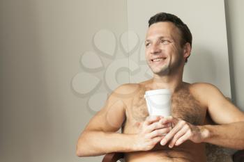 Portrait of young happy European man sitting with white paper cup of Coffee