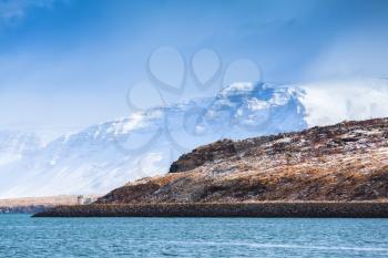 Coastal Icelandic landscape with snowy mountains under blue cloudy sky. Reykjavik area, Iceland
