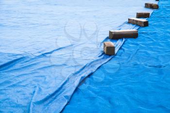 Blue industrial mesh textile with wooben planks covers ground area under construction