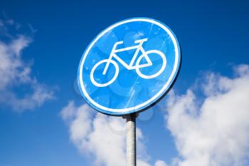 Bicycle lane, round blue road sign over cloudy sky background