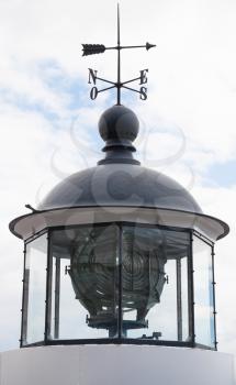 Classical Scandinavian white lighthouse tower, upper part with lamp and weather vane