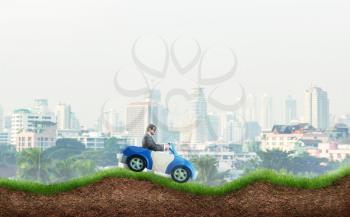 Young businessman driving a toy car on the hills