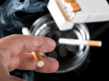 Smokers hand with ashtray and cigarettes pack on background