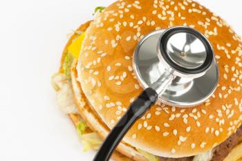 Fast food burger with medical stethoscope. Close-up view