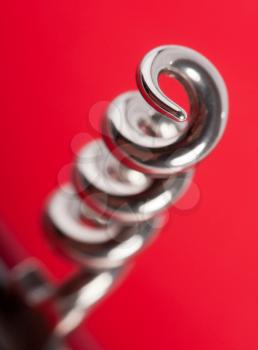 Close-up view of chrome corkscrew against red background