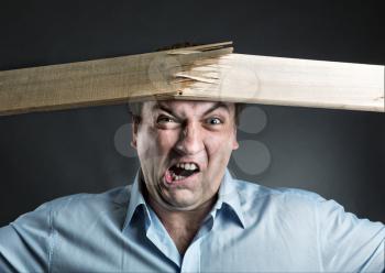 Angry strong man is breaking a wooden plank