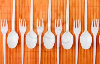 A row of plastic silverware. Spoons and forks