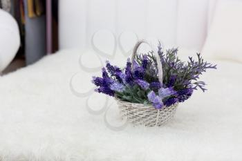 Violet flowers in a little basket on the bed