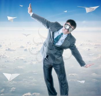 Businessman with paper planes and wearing goggles isolated on sky background