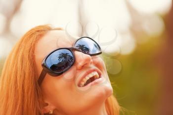 Happy girl with palm reflection in sunglasses