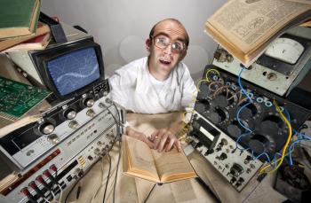 Funny timid scientist reading book at vintage technological laboratory