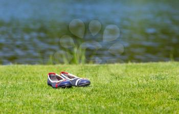Woman's shoes standing on the grass near the pond