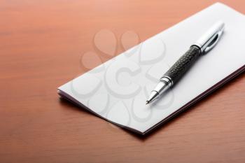 Pen and sheet of paper on a wooden table