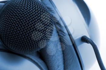 Close-up of professional studio microphone and headphones. Toned in blue