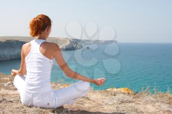 Woman in white meditating in mountains