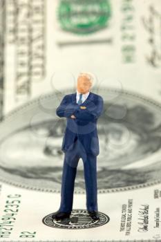 Miniature figurine of successful businessman on $100 banknote