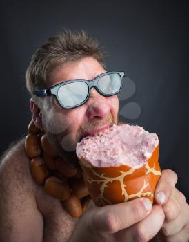 Hungry man with sausages round his neck eats a big wurst over grey