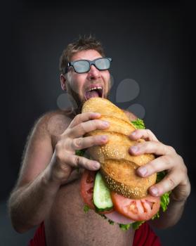 Fat happy man in glasses with sandwich over dark