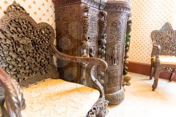 Luxurious wooden armchairs and cabinet with carved pattern