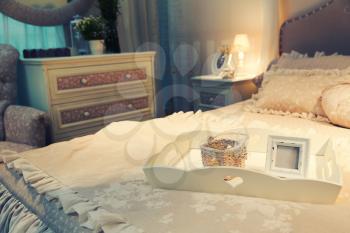 Nice luxury big white bed with pillows and frame in a bedroom