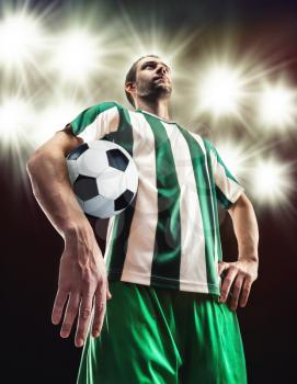 Football player holding a ball against light