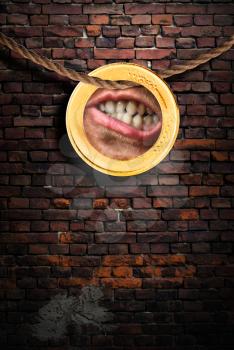Human mouth in the coin hanging on the rope against a brick wall