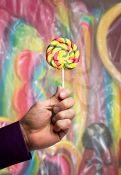Male hand holding a multicolored lollipop 